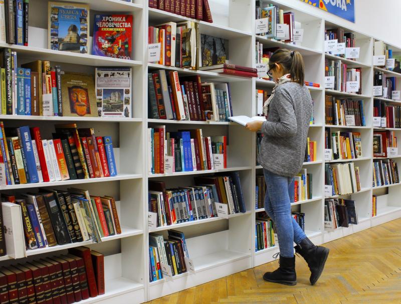 Student beside a bookcase in a library
